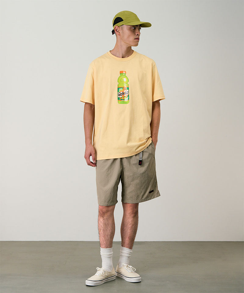 Model wearing milk tea colored Gramicci Nylon Packable G-Shorts and a mango colored shirt on a light-tone background.