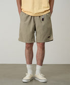 Model wearing milk tea colored Gramicci Nylon Packable G-Shorts and a mango colored shirt on a light-tone background.