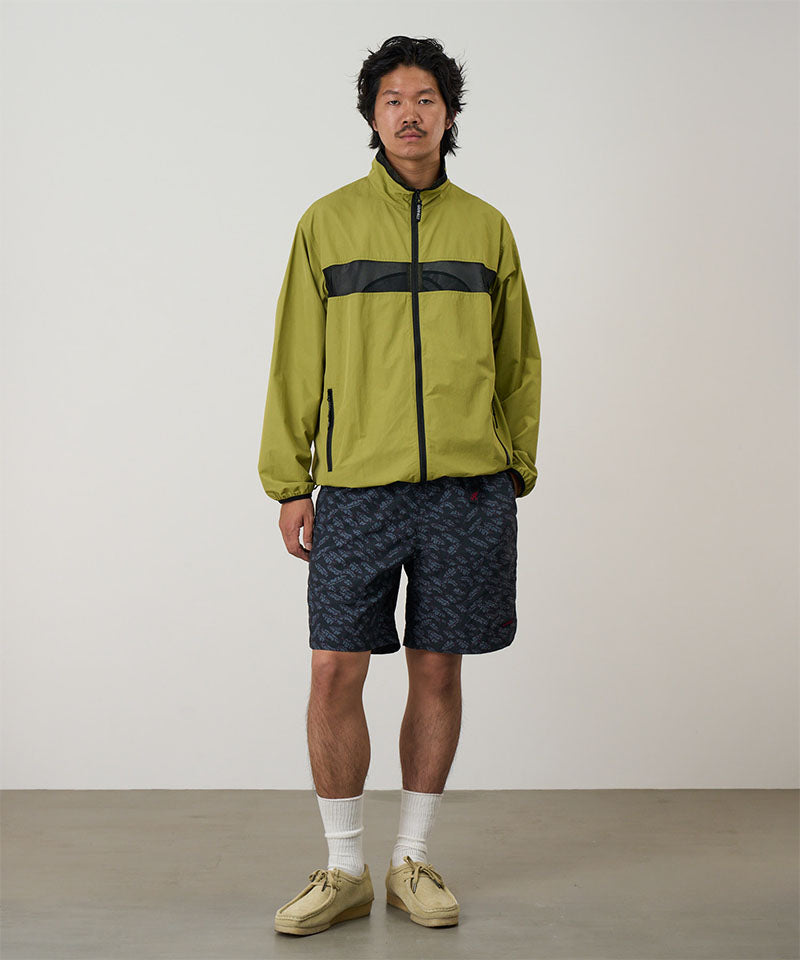 Model wearing navy leaf Gramicci Nylon Packable G-Shorts and a olive jacket on a light-tone background.