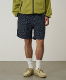 Model wearing navy leaf Gramicci Nylon Packable G-Shorts and a olive jacket on a light-tone background.