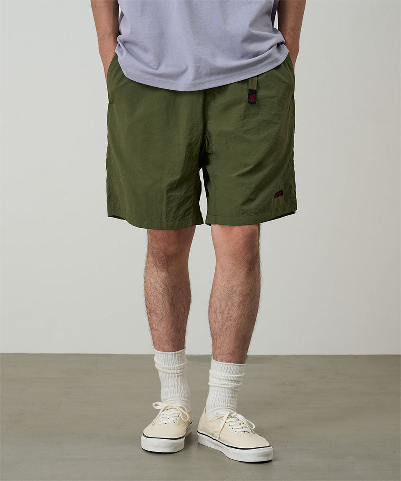Model wearing olive Gramicci Nylon Packable G-Shorts and a lavender shirt on a light-tone background.