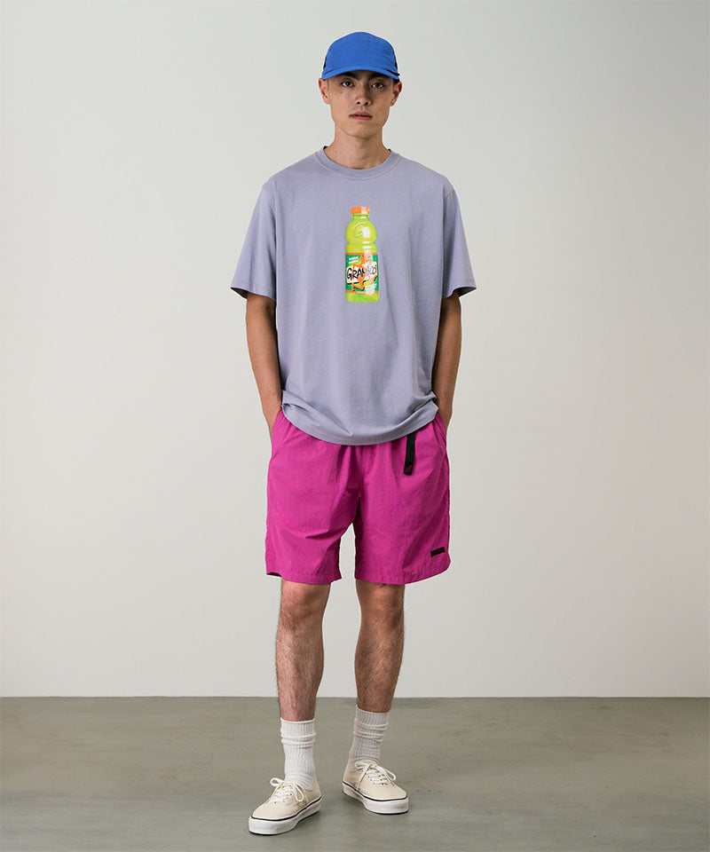 Model wearing bright plum colored Gramicci Nylon Packable G-Short and a lavender shirt on a light-tone background.