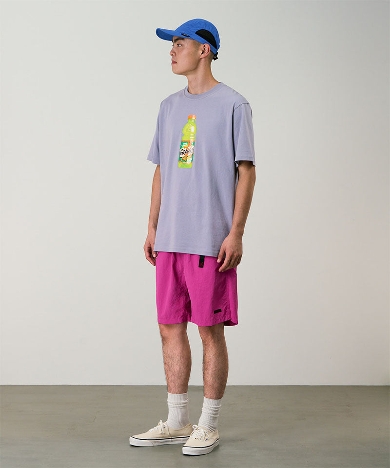 Model wearing bright plum colored Gramicci Nylon Packable G-Short and a lavender shirt on a light-tone background.