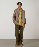 Model wearing bark pigment Gramicci EQT Pant and a plaid jacket on a light-tone background.