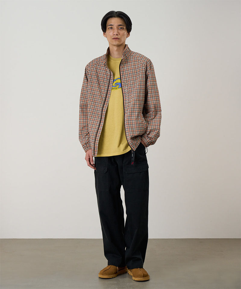 Model wearing black Gramicci EQT Pant and a plaid jacket on a light-tone background.