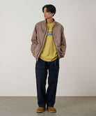 Model wearing double navy Gramicci EQT Pant and a plaid jacket on a light-tone background.