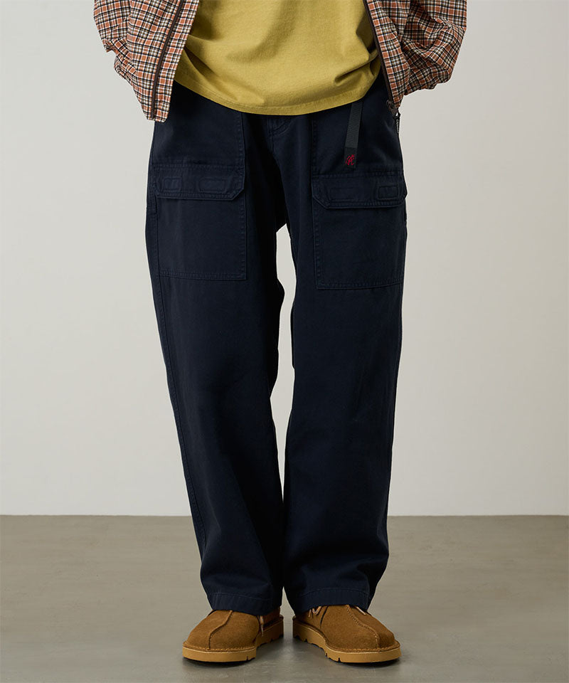 Model wearing double navy Gramicci EQT Pant and a plaid jacket on a light-tone background.
