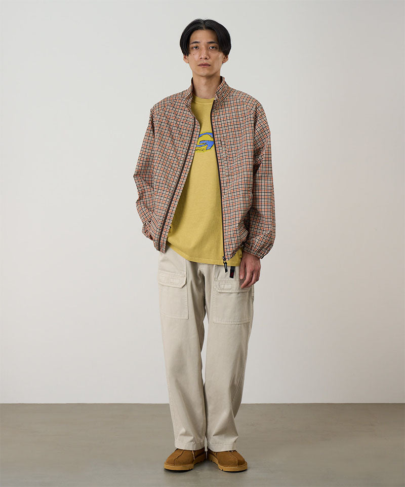 Model wearing sand pigment Gramicci EQT Pant and a plaid jacket on a light-tone background.