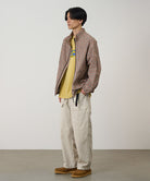 Model wearing sand pigment Gramicci EQT Pant and a plaid jacket on a light-tone background.