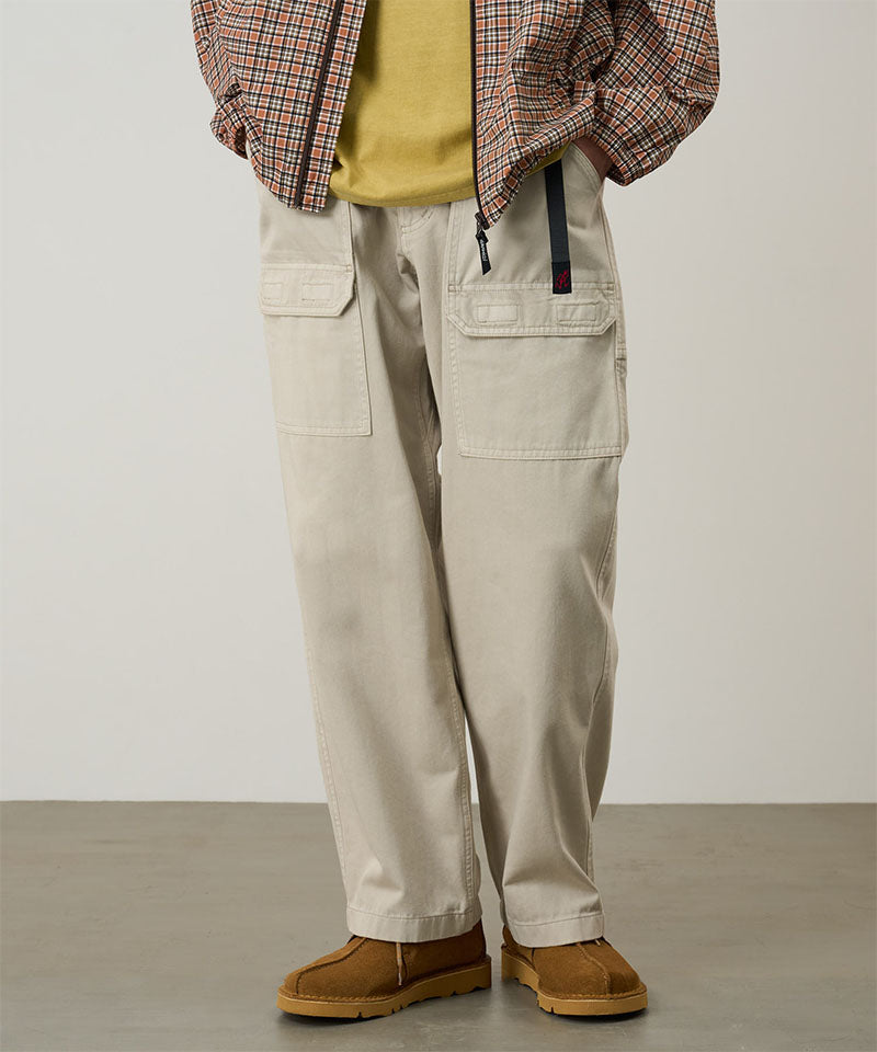 Model wearing sand pigment Gramicci EQT Pant and a plaid jacket on a light-tone background.