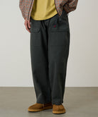 Model wearing smokey grey Gramicci EQT Pant and a plaid jacket on a light-tone background.