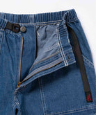 Close-up view of light wash colored Gramicci Gramicci Denim EQT Pant showing waistband and zipper detail on a light-tone background.