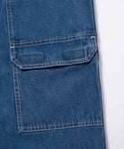 Close-up view of light wash colored Gramicci Denim EQT Pant pocket detail on a light-tone background.