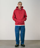 Model wearing light wash colored Gramicci Denim EQT Pant and a red hoodie on a light-tone background.