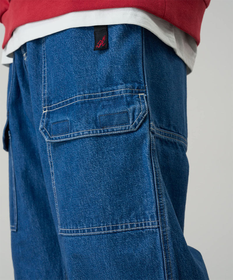 Model wearing light wash colored Gramicci Denim EQT Pant and a red sweatshirt on a light-tone background.