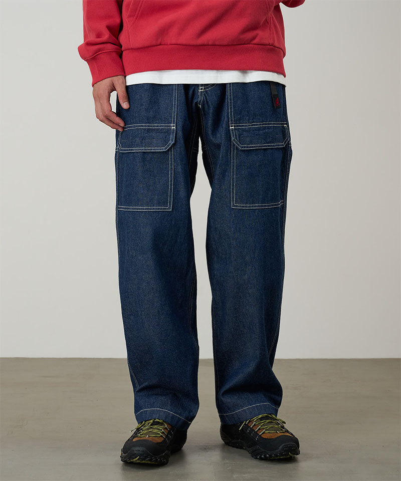Model wearing rinsed indigo Gramicci Denim EQT Pant and a red hoodie on a light-tone background.
