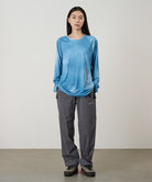 Model wearing a blue tie-dye Gramicci L/S 1st Layer shirt with grey graphic and grey pants on a light-tone background.
