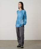 Model wearing a blue tie-dye Gramicci L/S 1st Layer shirt with grey graphic and grey pants on a light-tone background.