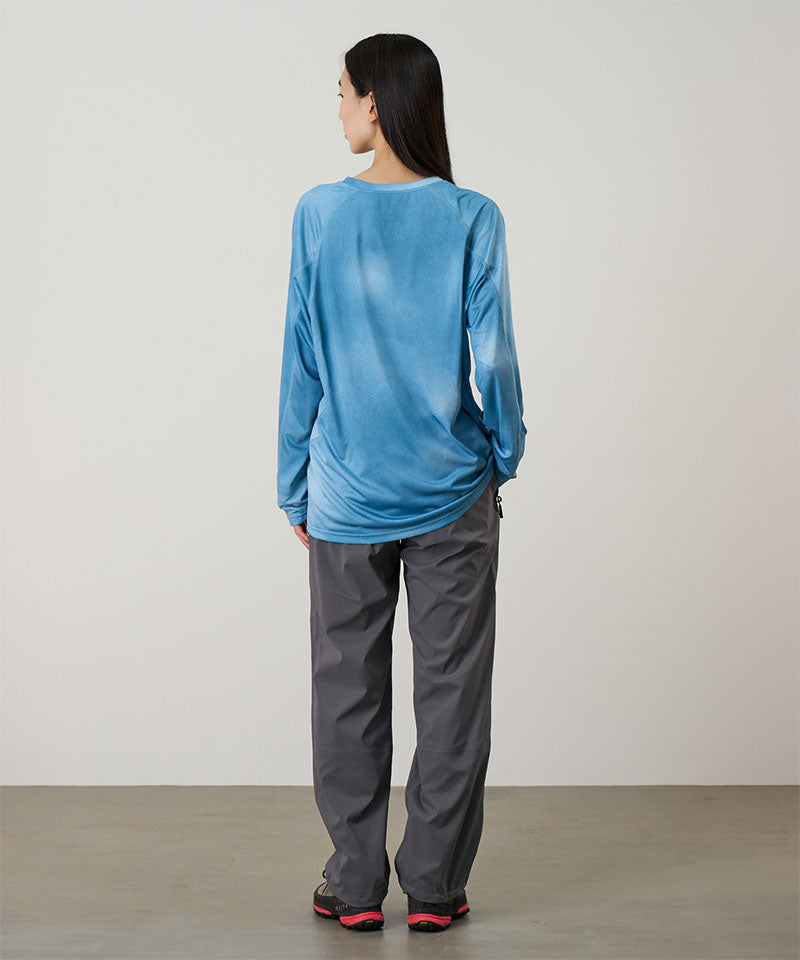 Back view of a model wearing a blue tie-dye Gramicci L/S 1st Layer shirt with grey graphic and grey pants on a light-tone background.