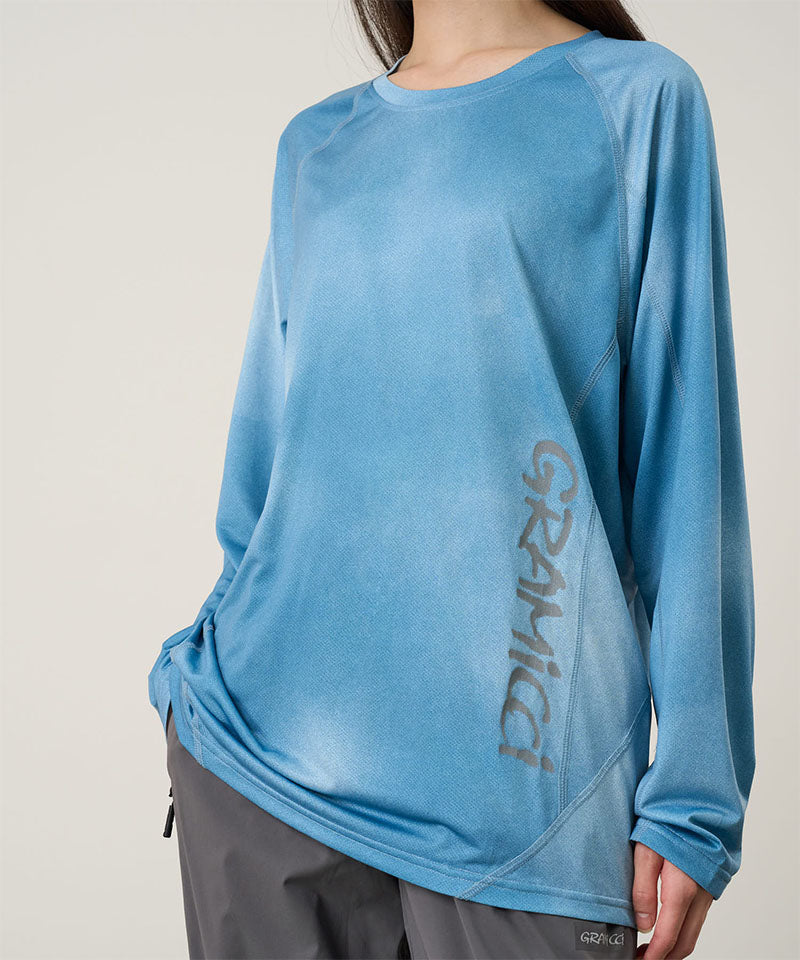 Model wearing a Gramicci blue tie-dye L/S 1st Layer shirt with grey graphic against a light-tone background.