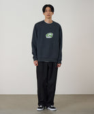 Model wearing a vintage black Gramicci G-Scribble Sweatshirt with a green graphic and black pants on a light tone background.