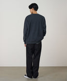 Back view of a model wearing a vintage black Gramicci G-Scribble Sweatshirt and black pants on a light tone background.