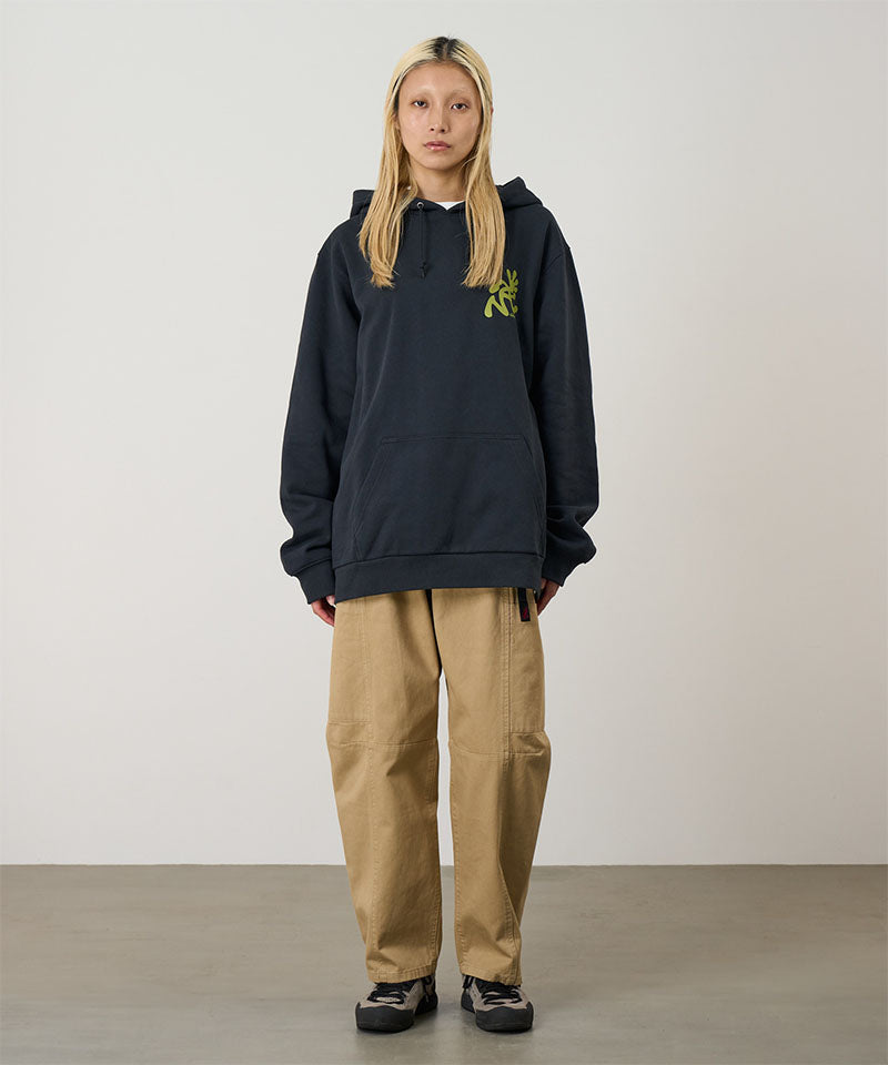 Model wearing a vintage black Gramicci Running Man Hooded Sweatshirt with an olive green graphic and khaki pants on a light-tone background.
