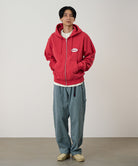 Person wearing a red hoodie and blue pants against a plain background