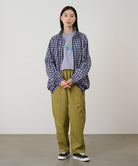 Model wearing grass colored Gramicci Swell Pant and a plaid jacket on a light-tone background.