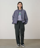 Model wearing shadow colored Gramicci Swell Pant and a plaid jacket on a light-tone background.