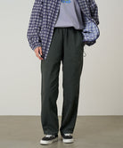 Model wearing shadow colored Gramicci Swell Pant and a plaid jacket on a light-tone background.