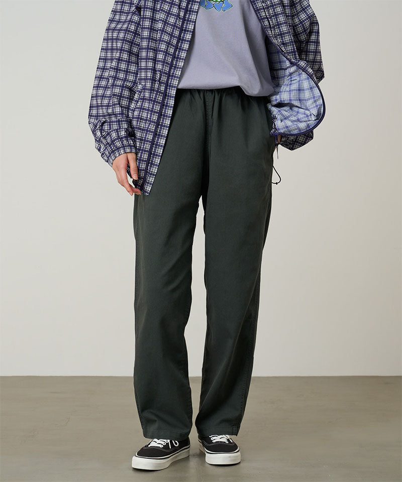 Model wearing shadow colored Gramicci Swell Pant and a plaid jacket on a light-tone background.