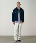 Model wearing stone colored Gramicci Swell Pant and a blue denim jacket on a light-tone background.