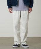 Model wearing stone colored Gramicci Swell Pant and a blue denim jacket on a light-tone background.