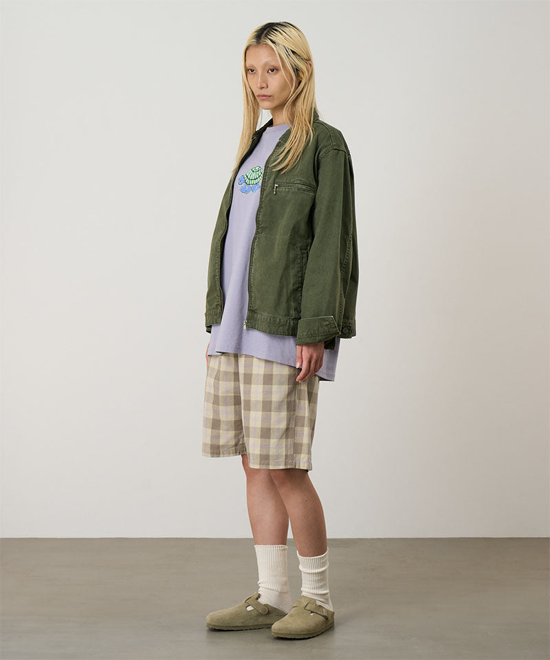 Model wearing shadow plaid colored Gramicci Swell Short Shadow Plaid and a olive jacket on a light-tone background.