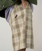 Model wearing shadow plaid colored Gramicci Swell Short Shadow Plaid and a olive jacket on a light-tone background.