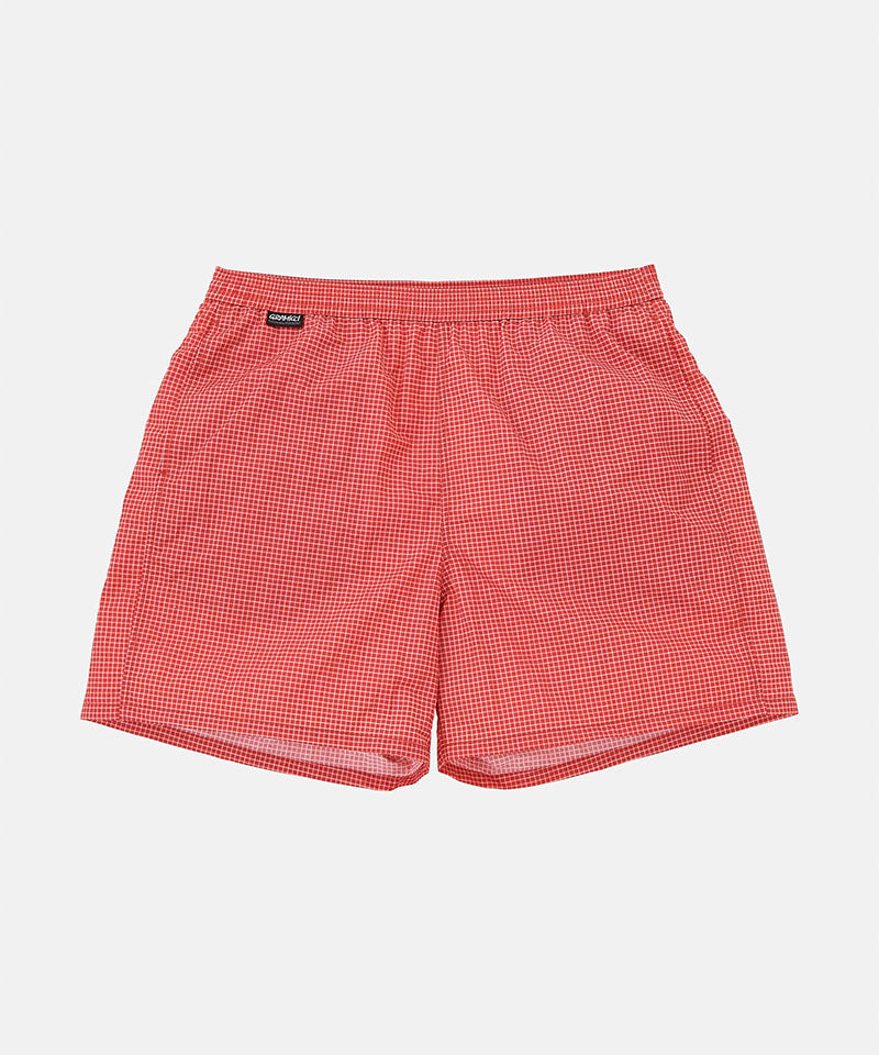 Front view of red checked Gramicci Grid Swim Shorts against a light-tone background.
