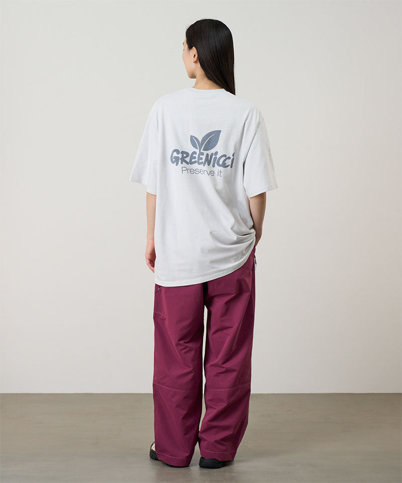 Back 
view of a model wearing a smoke colored Gramicci Greenicci Tee with a graphic and purple pants on a light tone background.
