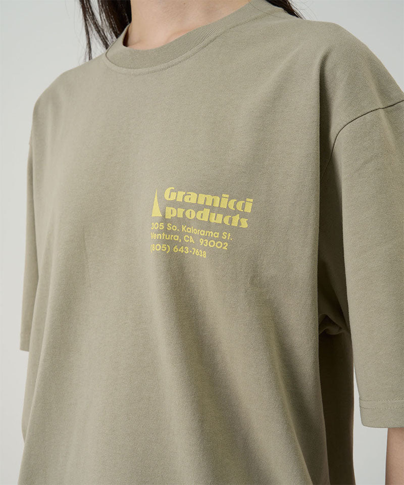Model wearing a Gramicci beige G-Sail Tee with a yellow graphic against a light-tone background.