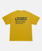 Back view of a Gramicci yellow G-Sail Tee with black graphic against a light-tone background.