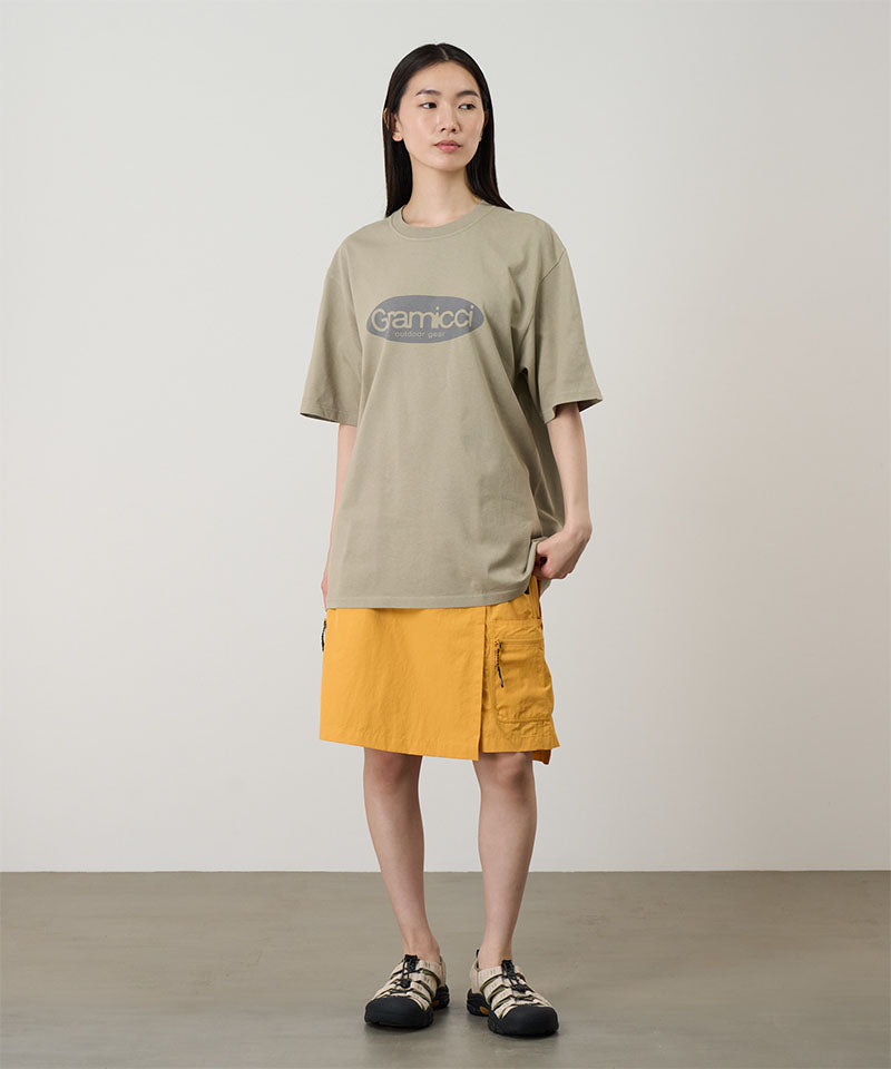 Model wearing a beige Gramicci Outdoor Gear Tee with a grey graphic and yellow skort on a light-tone background.