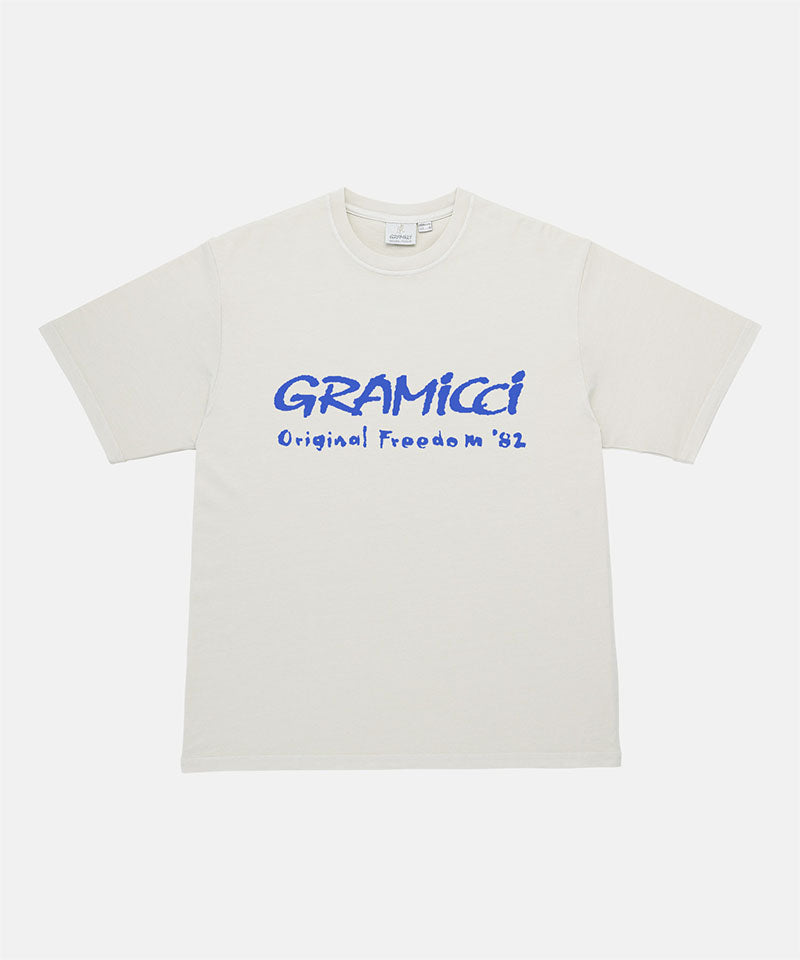 Gramicci natural pigment Freedom Tee Pigment Dyed with blue graphic against a light tone background.