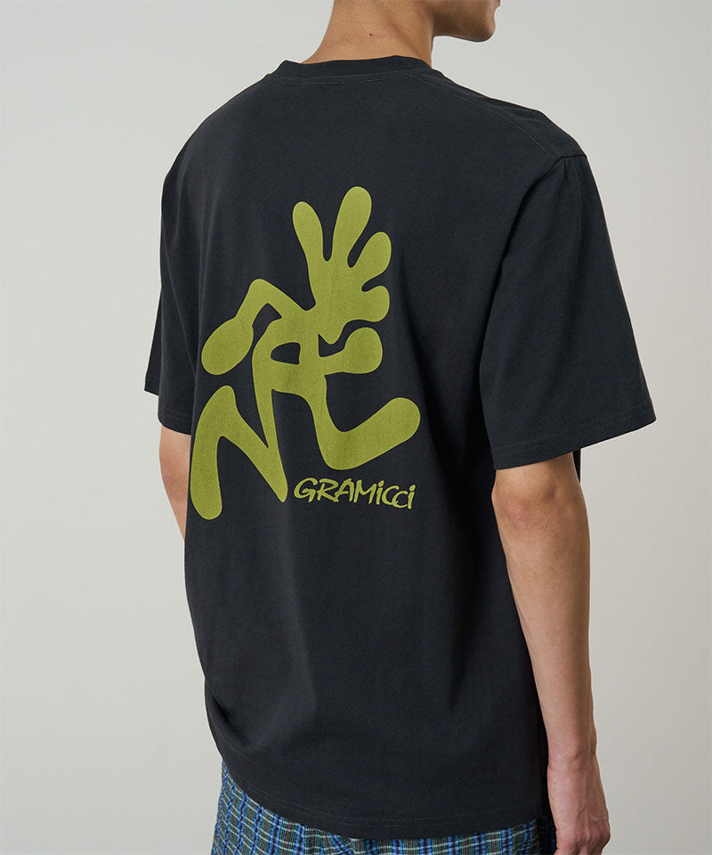 Back view of a model wearing a Gramicci vintage black Running Man Tee with lime green graphic against a light-tone background.