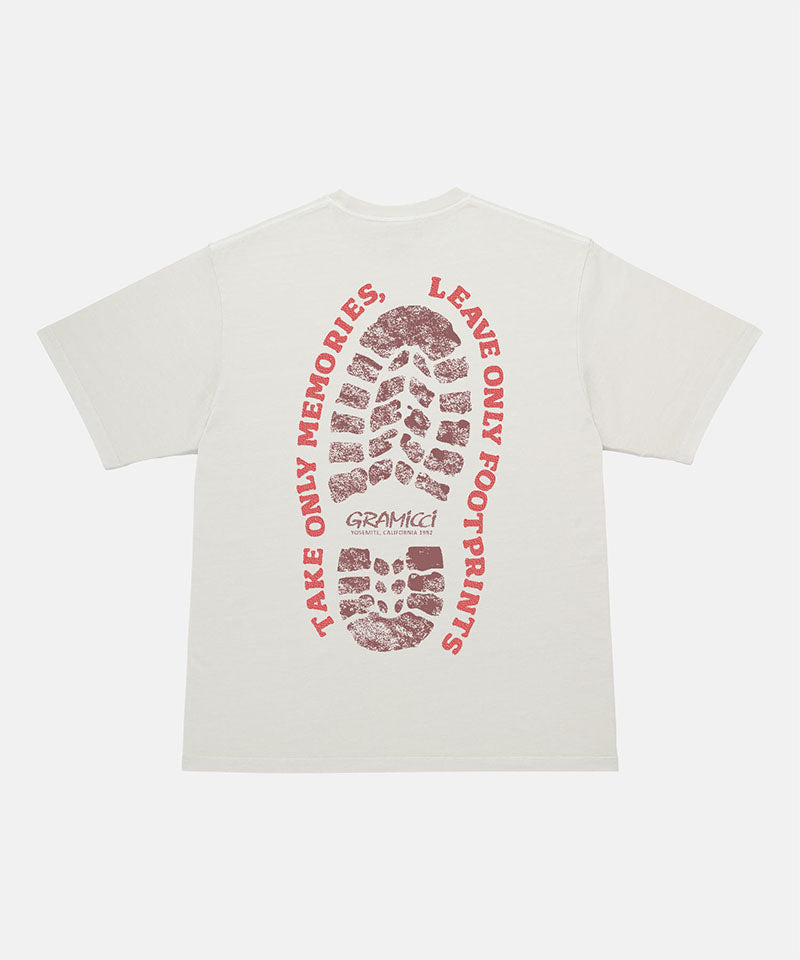 Back view of a Gramicci natural pigment Footprints Tee Pigment Dyed with red graphic against a light tone background.
