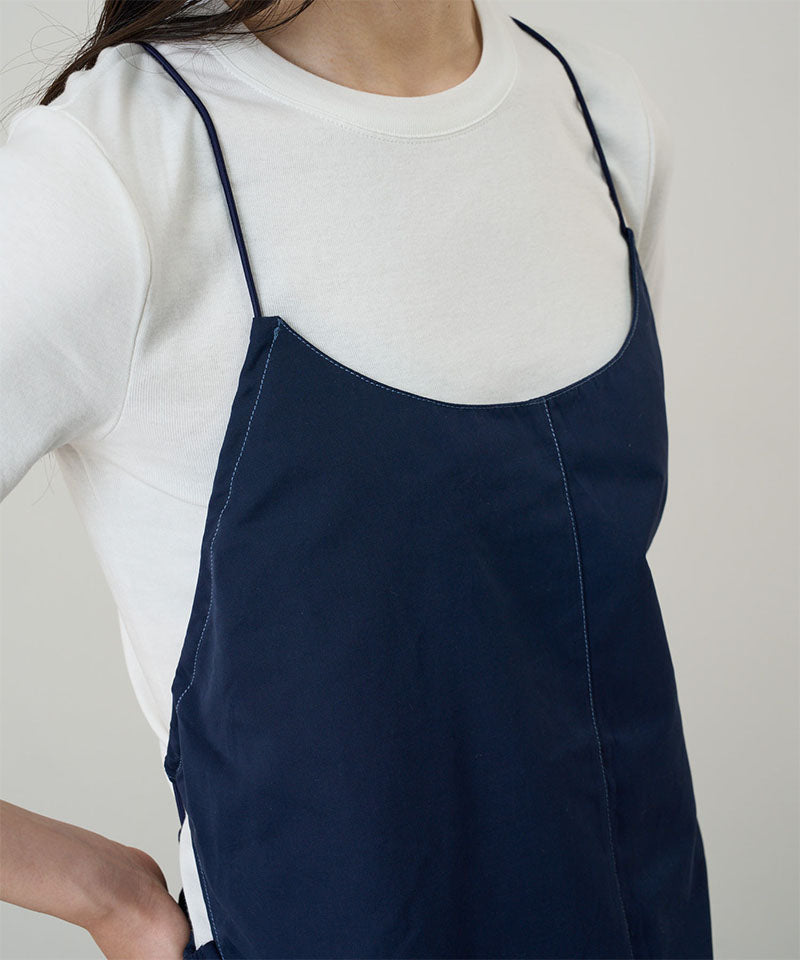 Model wearing a Gramicci Women's Woven Milton Dress in the color dark navy and a white undershirt on a light-tone background.
