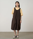 Model wearing a chocolate colored Gramicci Nylon Dress and a yellow shirt on a light-tone background.