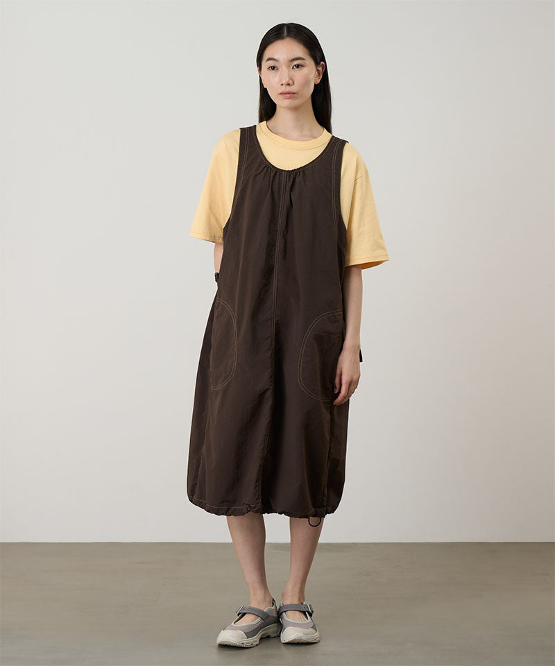 Model wearing a chocolate colored Gramicci Nylon Dress and a yellow shirt on a light-tone background.