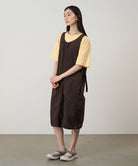 Model wearing a chocolate colored Gramicci Nylon Dress and a yellow shirt on a light-tone background.