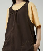 Model wearing a chocolate colored Gramicci Nylon Dress and a yellow shirt on a light-tone background.
