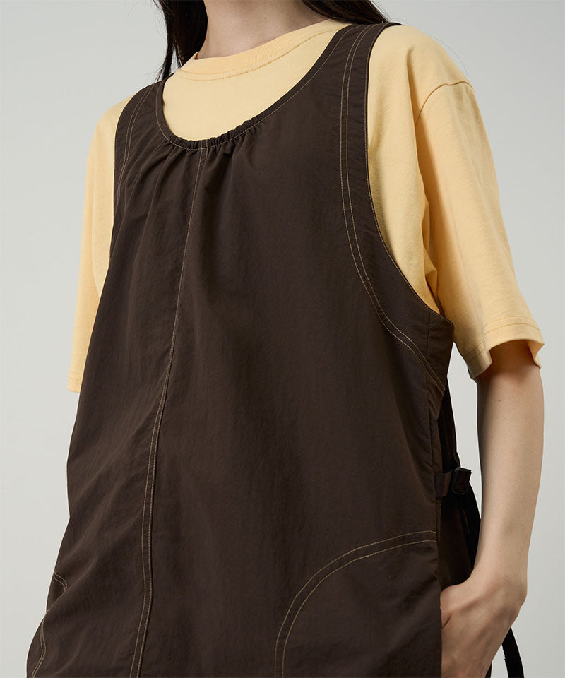 Model wearing a chocolate colored Gramicci Nylon Dress and a yellow shirt on a light-tone background.